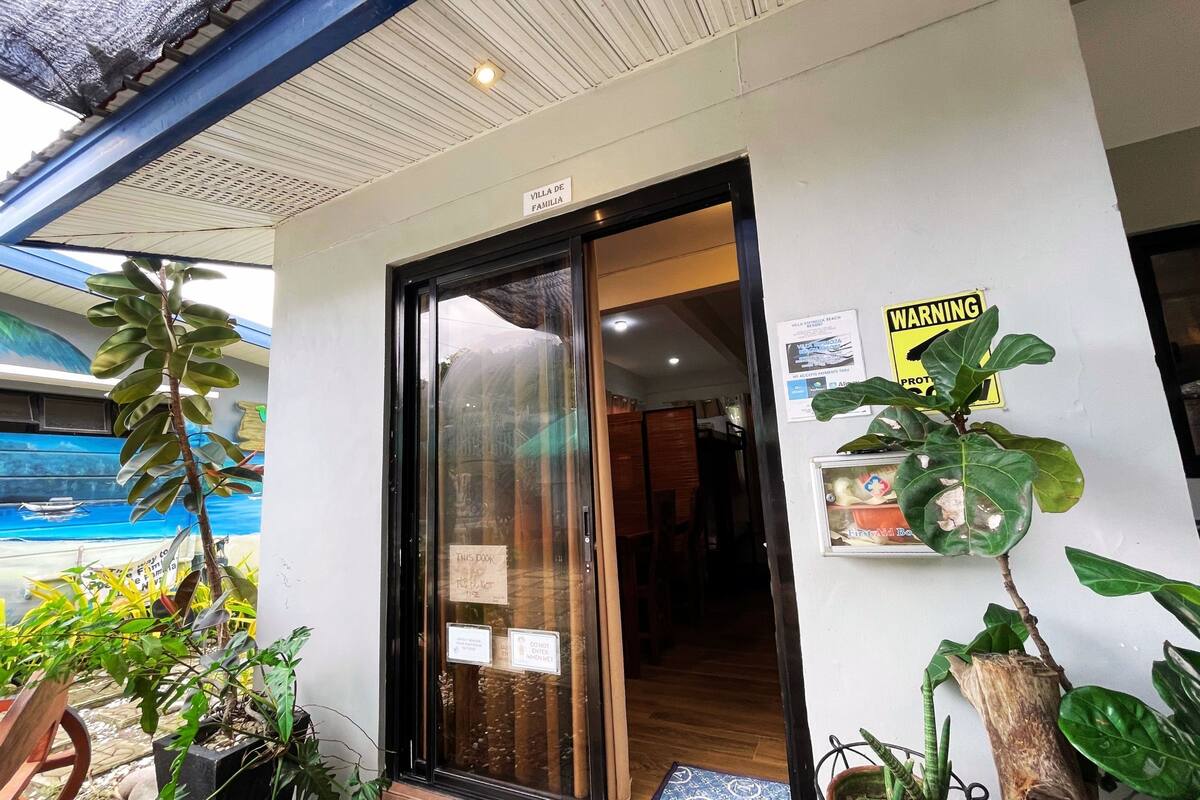 A hotel entrance with a glass door, a warning sign, and a potted plant.