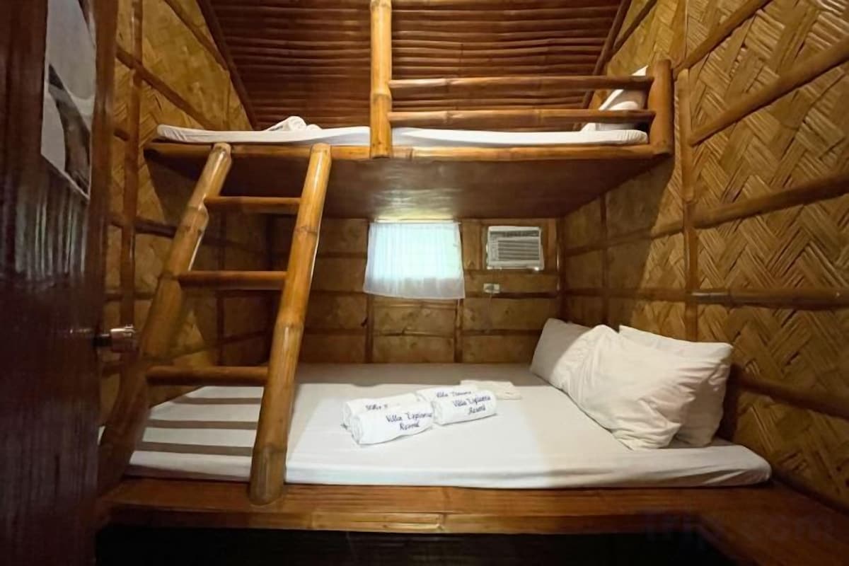 A bunk bed with a ladder, a bedside table, and a window with a curtain.