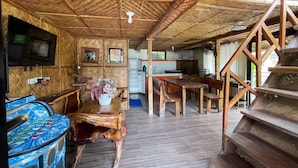 A wooden interior with a TV, dining area, and staircase.