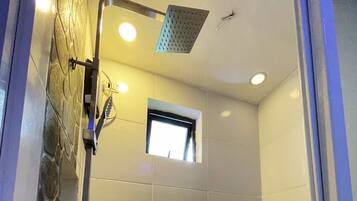 A shower with a handheld showerhead and a window above it.
