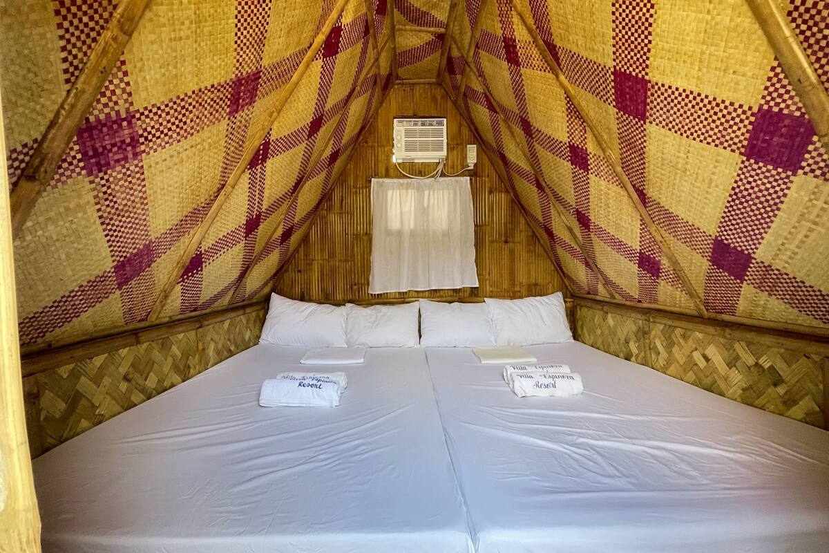 A cozy, triangular room with a checkered patterned wall and a bed with white linens and towels.