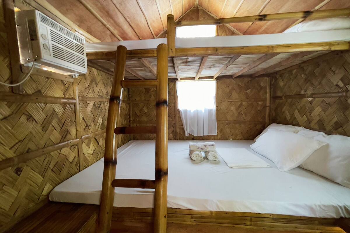 A bunk bed with a ladder, a white mattress, and a small table with a towel and a book.