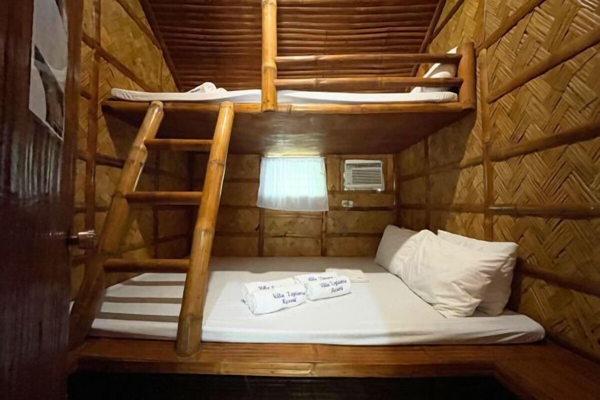 A bunk bed room with a ladder, a window with a curtain, and a bed with neatly folded towels.