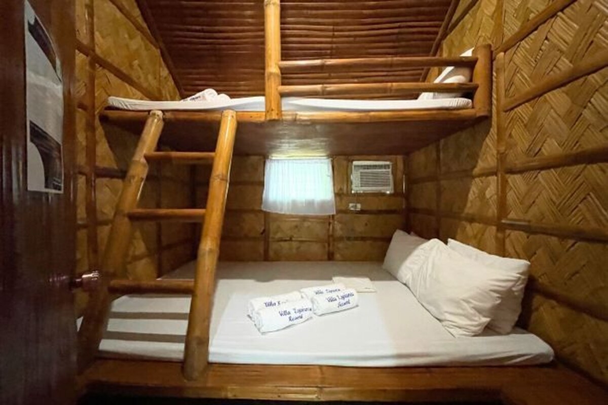 A bunk bed room with a ladder, a window with a curtain, and a bed with a white sheet and pillows.