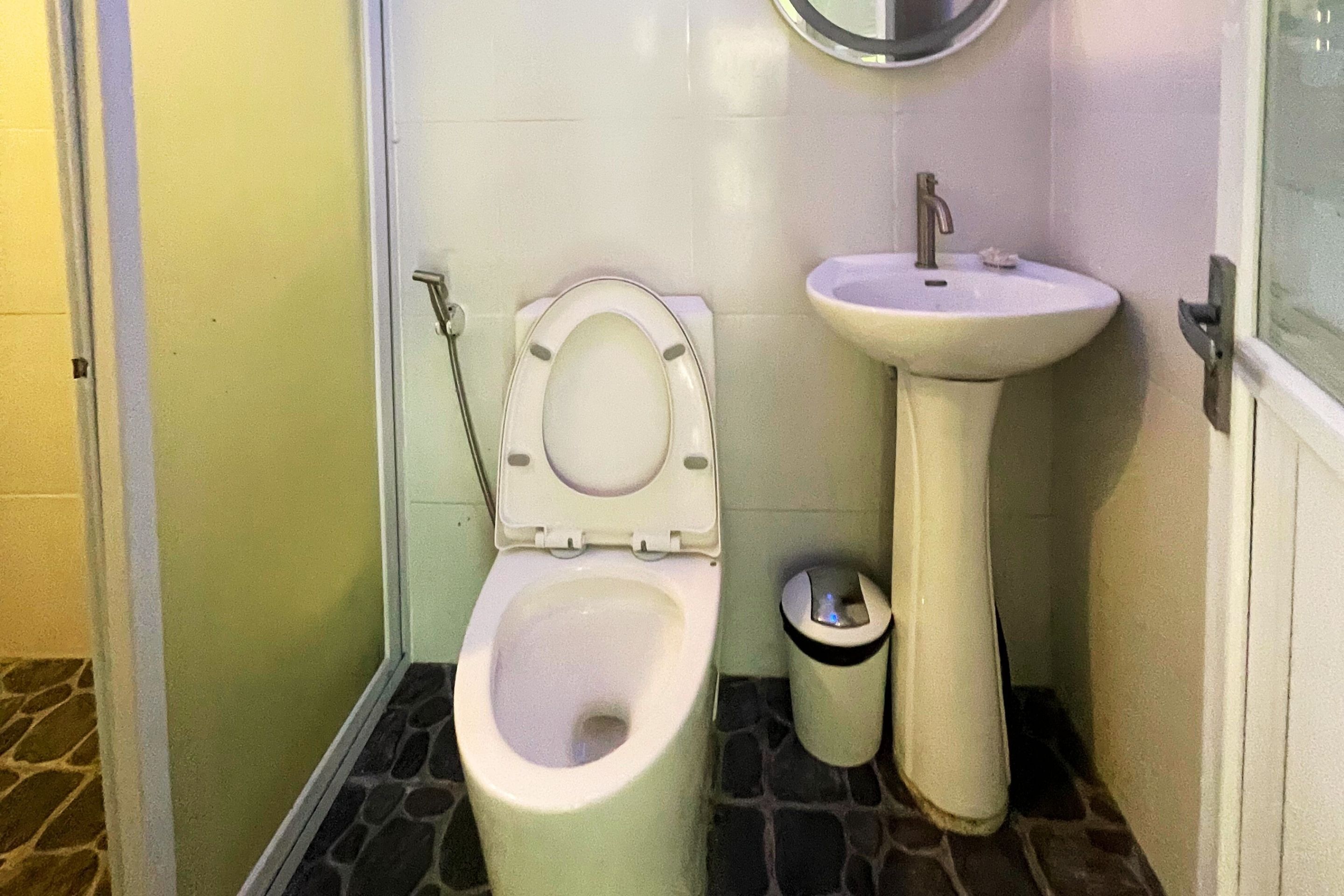 Casa de banho com sanita, lavatório e lixeira.