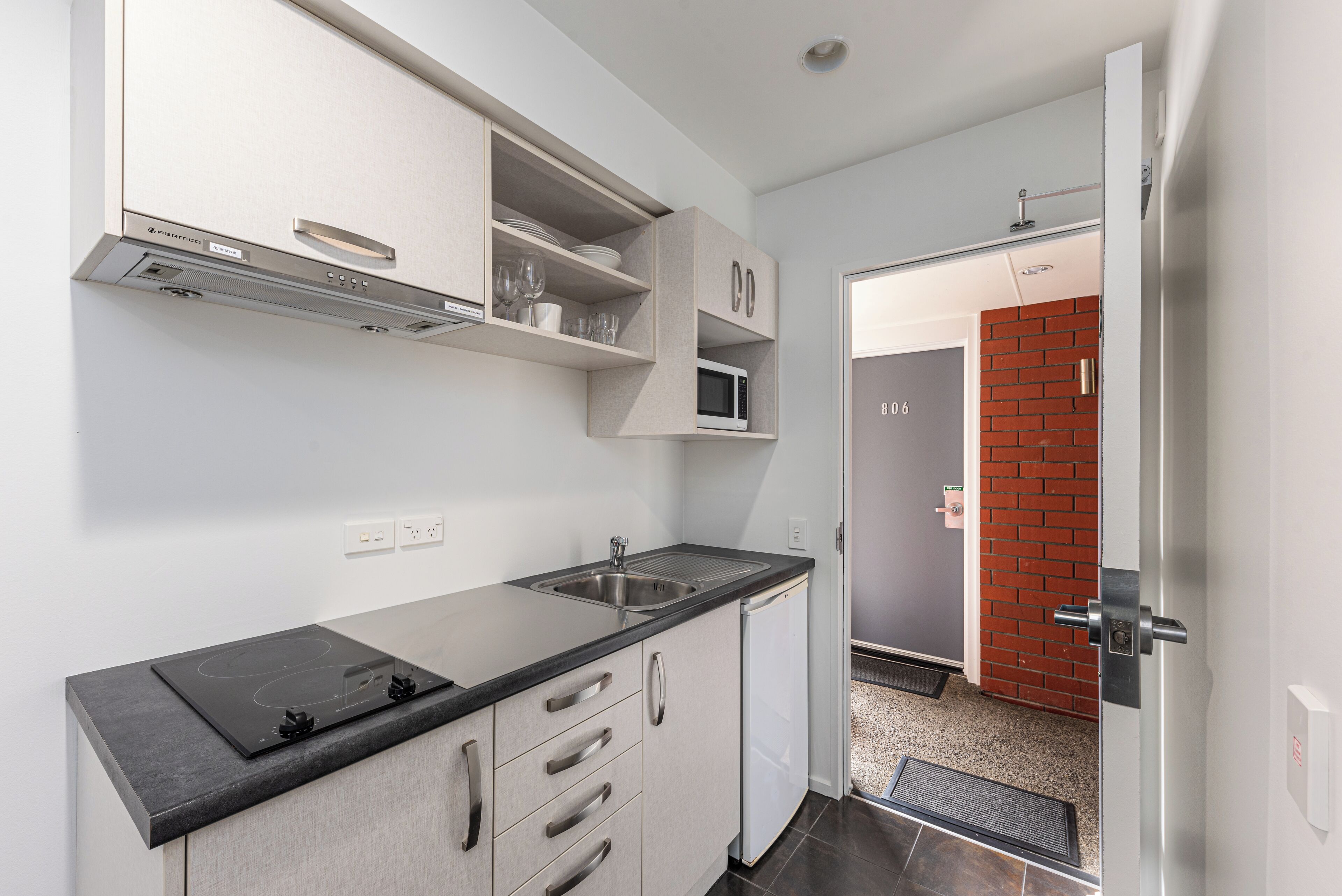 A modern kitchen with a built-in microwave, a stainless steel sink, and a black countertop.