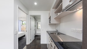 A modern kitchen with dark tiles, stainless steel appliances, and a black countertop. - 315 motel Riccarton (Christchurch)