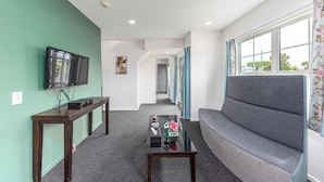 A living room with a sofa, a coffee table, a TV, and a hallway leading to another room. - 315 motel Riccarton (Christchurch)