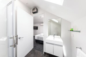 A modern hotel room with a glass shower enclosure, a white sink, and a large mirror. - 315 motel Riccarton (Christchurch)