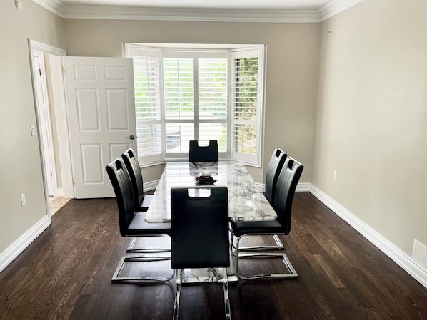 A dining room with a rectangular table, six chairs, and a window with blinds.