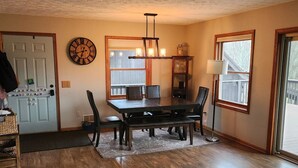 A dining area with a wooden table, chairs, a clock, and a window with a view. - Dream Country Getaway 27 Acres in Conesus, NY! New Game Room! (Conesus)