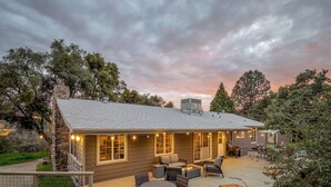 Ein Haus mit einer Terrasse, Sitzgelegenheiten im Freien und Lichterketten.
