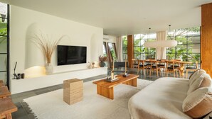 Ein modernes Wohnzimmer mit Flachbildfernseher, Couchtisch aus Holz und einer Couch.
