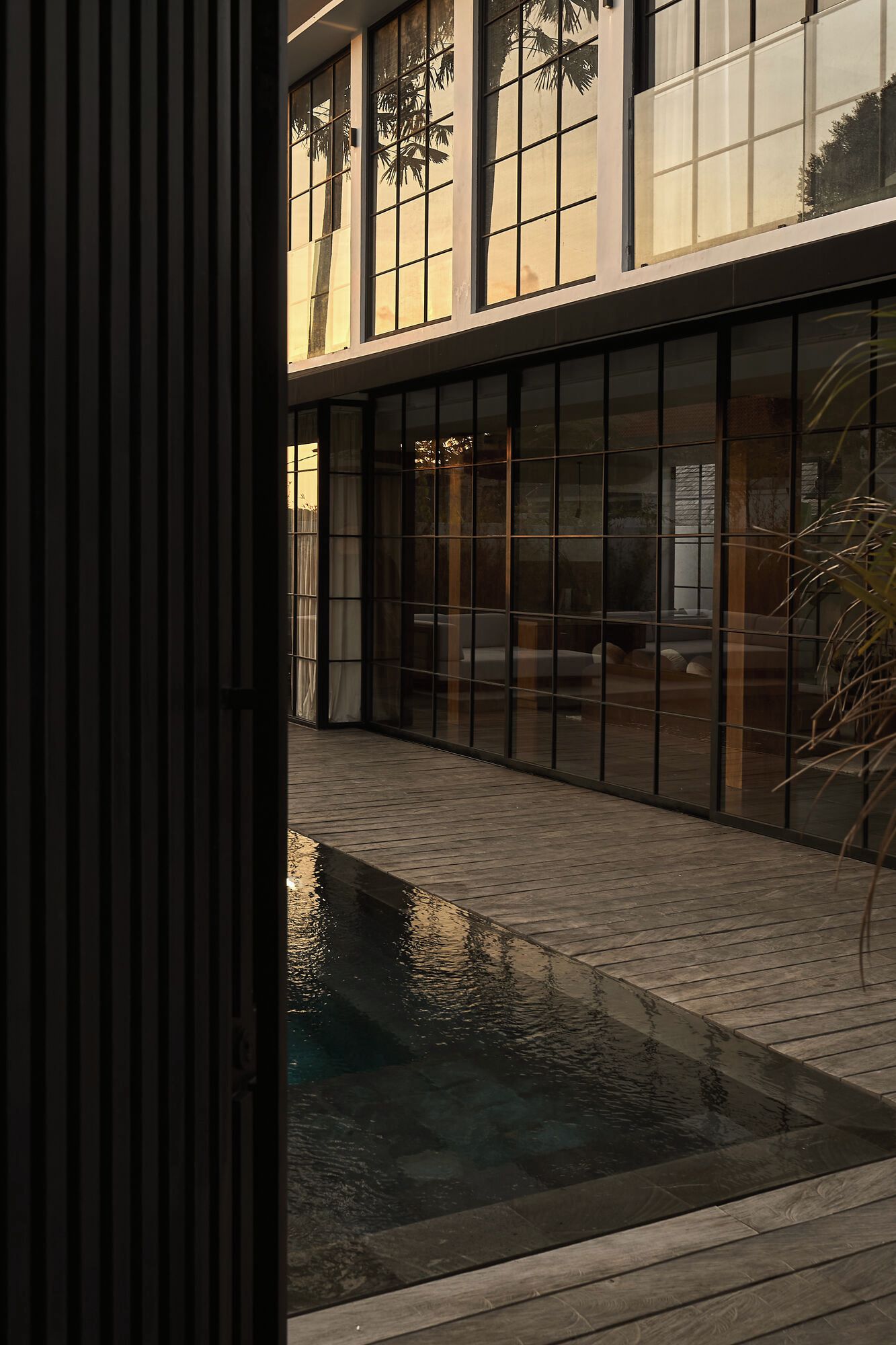 Un bâtiment moderne doté de grandes fenêtres et d’un élément décoratif aquatique réfléchissant dans la cour.