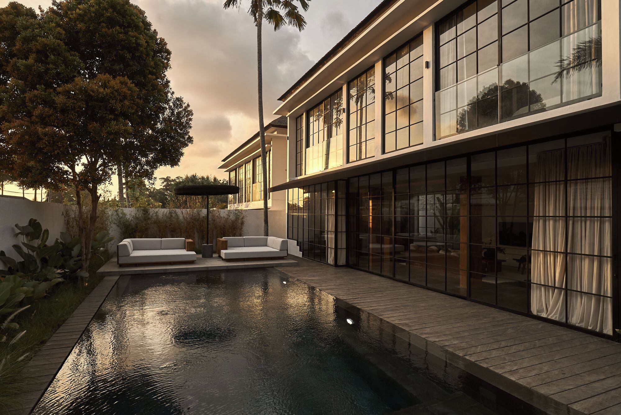 A modern house with a swimming pool, large windows, and outdoor seating.