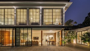 Ein modernes, zweistöckiges Haus mit großen Glasfenstern, einem Essbereich und einem Pool.
