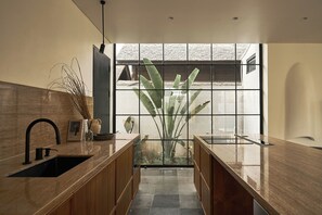 Una cocina moderna con una isla central, pileta integrada y un amplio ventanal con vistas al exterior.