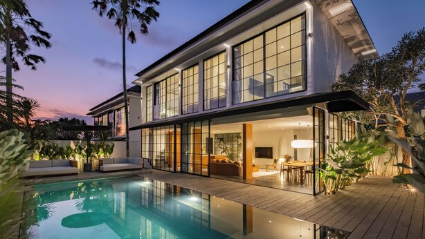 Ein modernes, zweistöckiges Haus mit Swimmingpool, großen Fenstern und einer Terrasse.