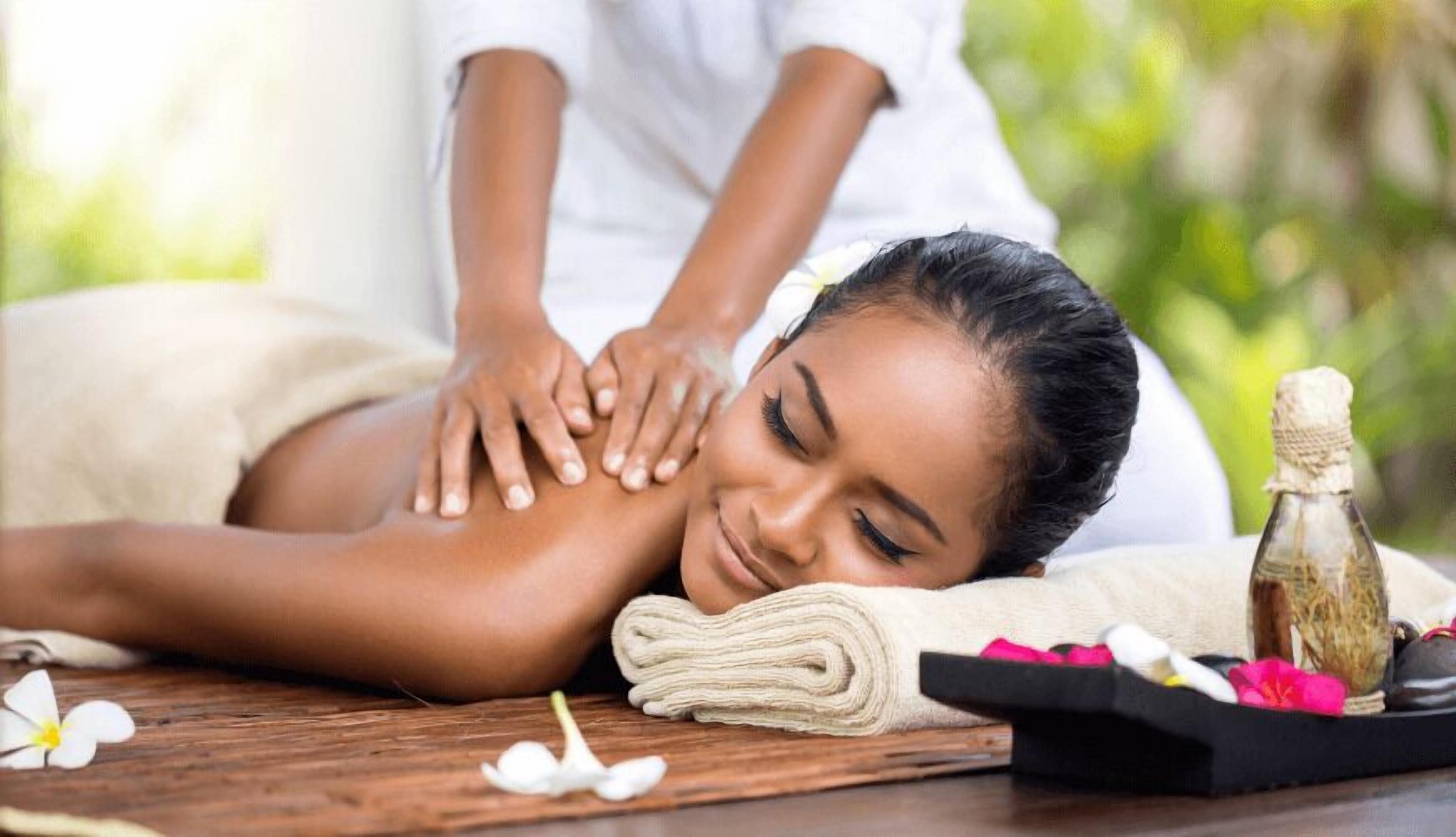 A massage therapy session with a wooden table, a towel, and a bottle of oil.