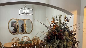 A dining area with a round table, chairs, a mirror, and a floral arrangement. - Spacious 4-bedroom house in charming Pflugerville/Round Rock with WiFi, AC (Round Rock)
