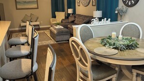 A dining area with a round table, chairs, and a chandelier. There is a sofa and a chair in the background. - Spacious 4-bedroom house in charming Pflugerville/Round Rock with WiFi, AC (Round Rock)