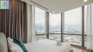 Ein modernes Hotelzimmer mit einem großen Bett und Blick auf die Stadt durch große Fenster sowie ein Stadtblick vom Fenster aus.