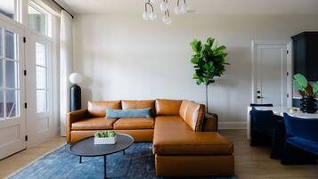 A modern living room with a leather sectional sofa, a round coffee table, and a large plant.