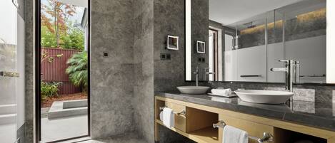 Un baño moderno con un espejo grande, dos lavamanos y un mueble de tocador de madera.