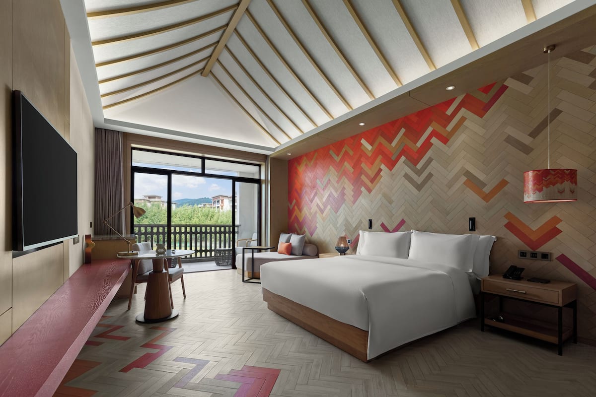 Habitación de hotel moderna con una cama grande, un escritorio y vistas al exterior.