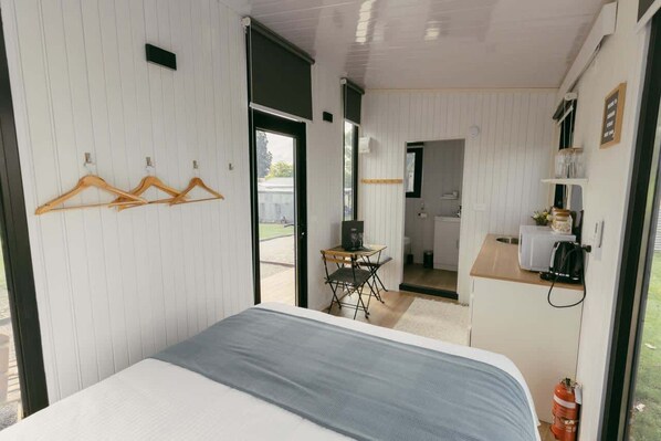 A compact room with a bed, a small kitchenette, and a dining area.