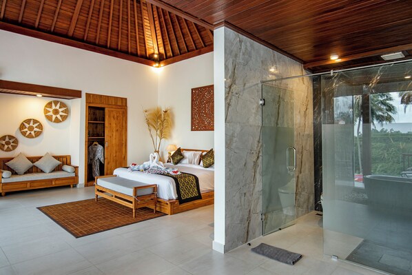 A spacious bedroom with a large bed, a wooden ceiling, a glass shower, and a view of the outdoors.