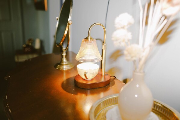 A table with a lamp, a cup, and a vase with flowers. - Unique Stay at the Historic Train House 2.5 miles from Stadium - King Bed (Northport)