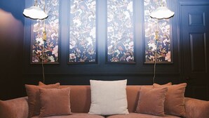 Una habitación con un sofá marrón, una almohada blanca y tres cuadros florales en la pared.