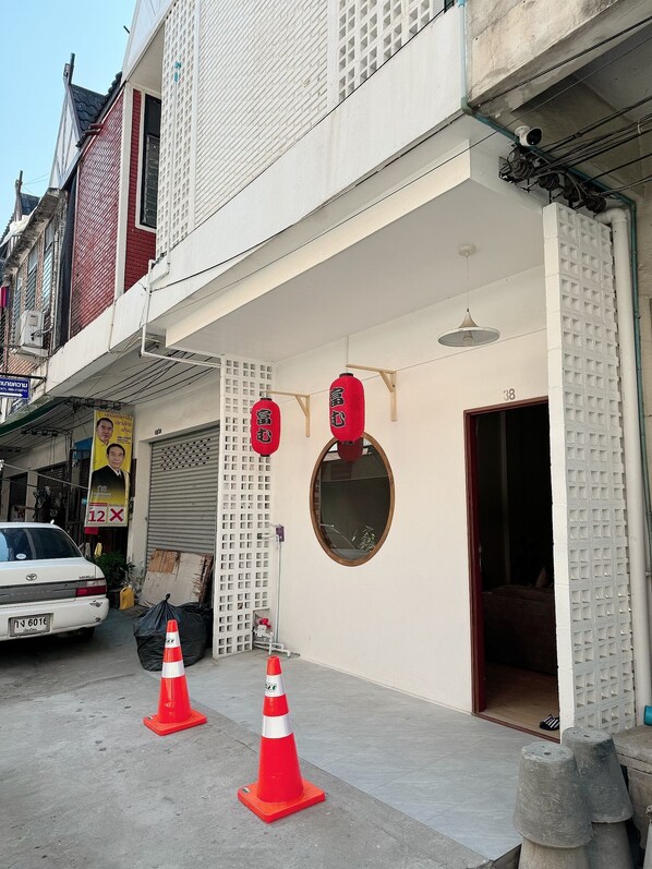 Un edificio con fachada blanca, el número '38' visible y una puerta roja.