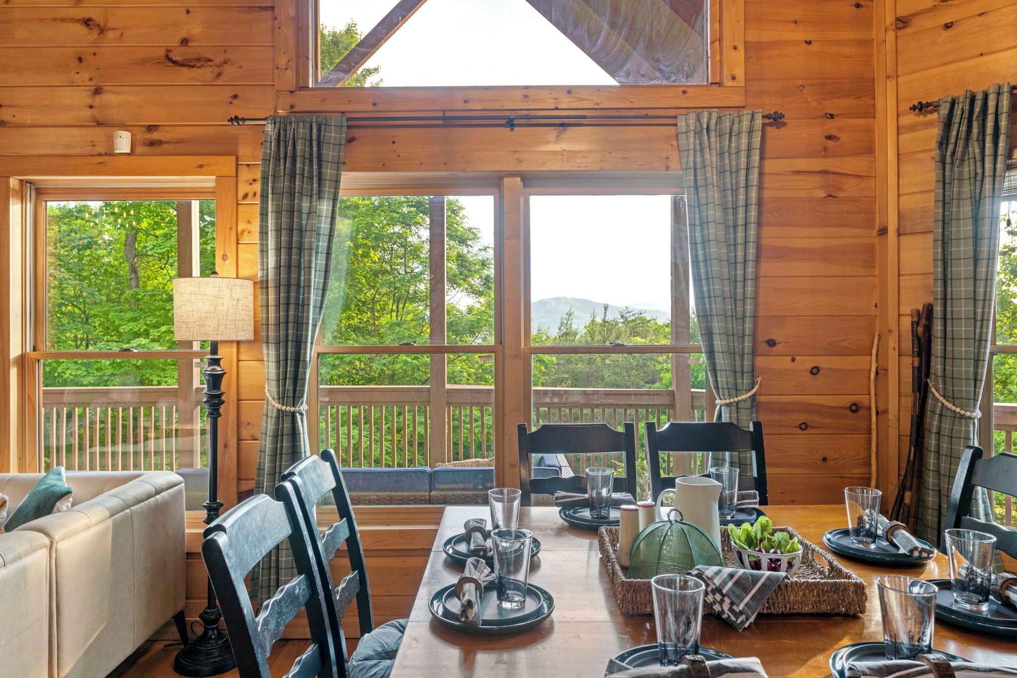 Une cabane en bois avec un coin repas, de grandes fenêtres et une vue sur la verdure.