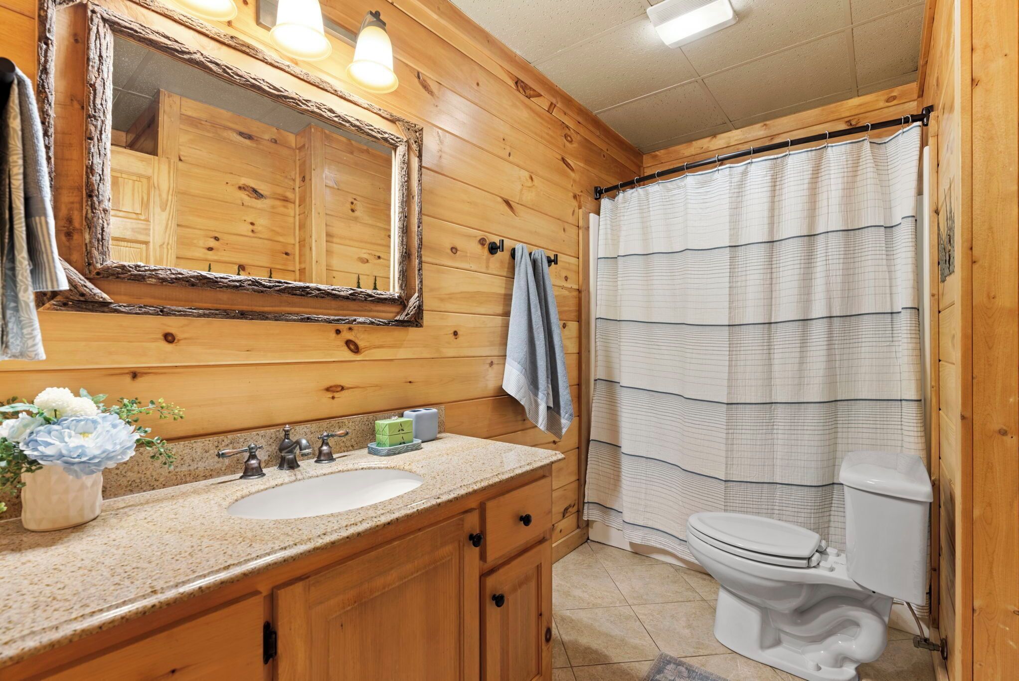 A wooden bathroom with a sink, mirror, and toilet.