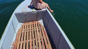 A person sitting on a boat with a view of mountains and a clear sky. - Titicaca Glampina (Puno)
