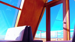 A room with a sloped ceiling, two cushioned seating areas, and a view of the landscape through large windows. - Titicaca Glampina (Puno)