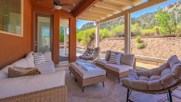A covered outdoor seating area with wicker furniture and a ceiling fan. - Zion view~Hot Tub~Fire Pit~Sauna~Stargazing (Apple Valley)