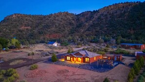 A modern house with a large patio, surrounded by a dry, hilly landscape. - Zion view~Hot Tub~Fire Pit~Sauna~Stargazing (Apple Valley)