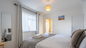 Un lit bien fait, avec une couverture matelassée, une table de chevet et une fenêtre avec des rideaux.