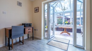 Une pièce comprenant un bureau, une chaise et une grande porte vitrée donnant sur un espace extérieur aménagé avec une table et des chaises.