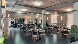 Un restaurante amplio con un interior moderno, que presenta un techo con diseño, varias mesas de comedor e iluminación ambiental.