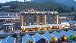 Un hotel de varios pisos con fachada de piedra, múltiples balcones y zonas de estar al aire libre.