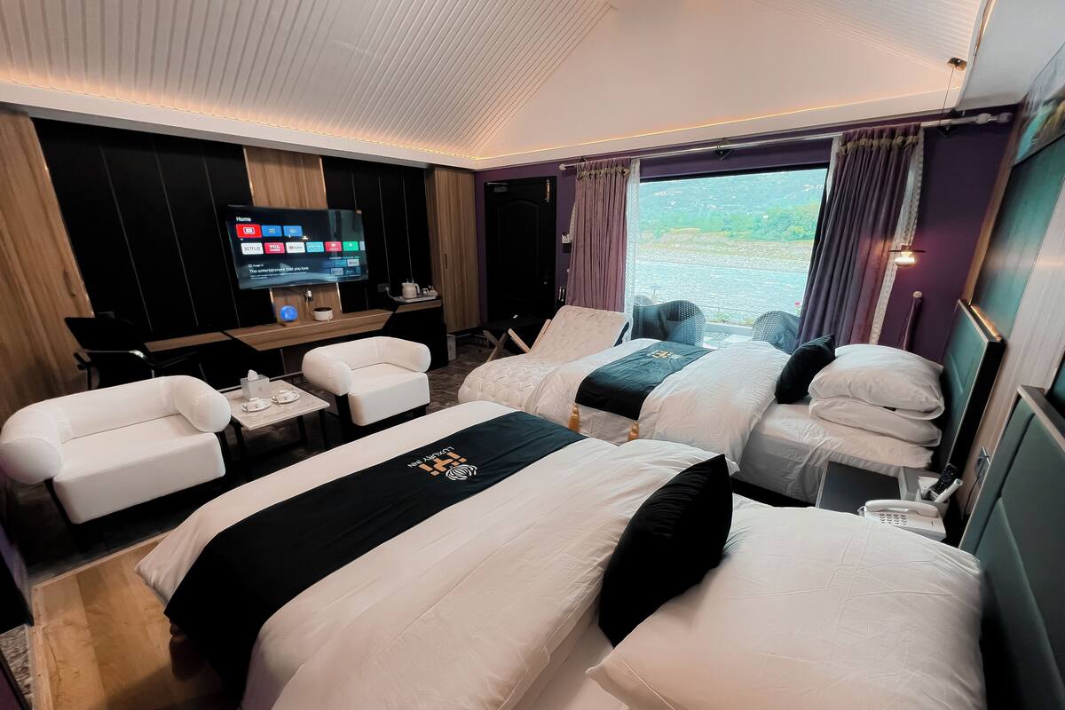 Une chambre d’hôtel avec deux lits, un bureau, une télévision et une vue sur l’extérieur.