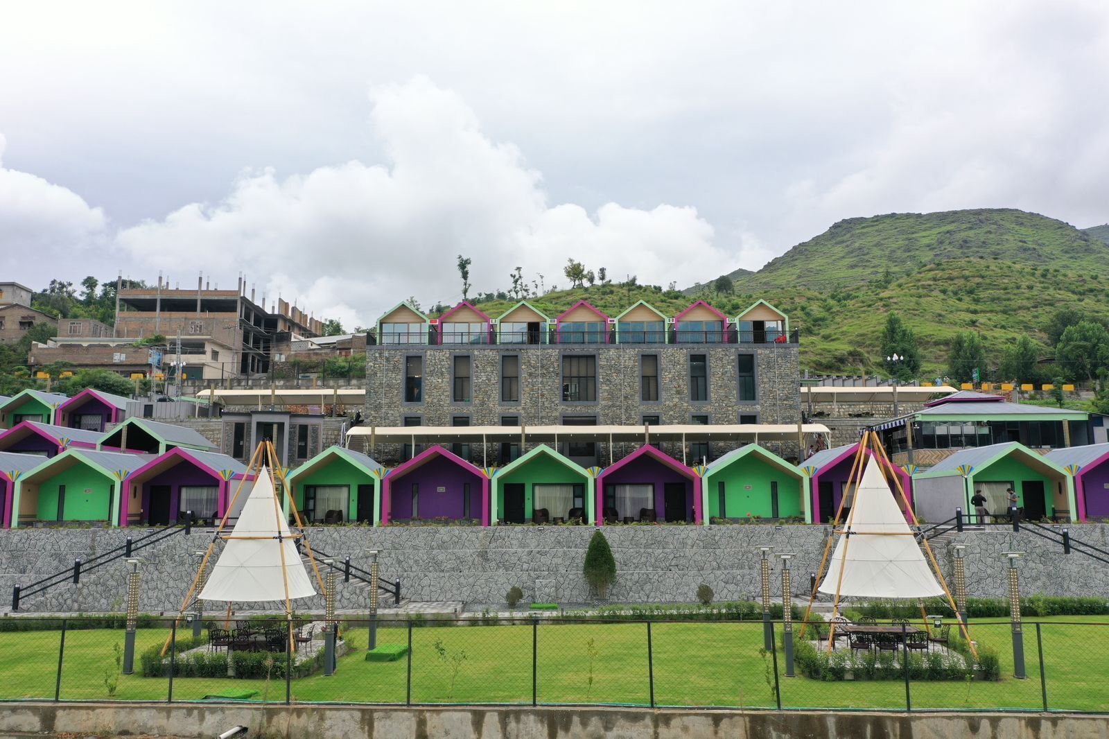 A hotel with colorful cabins and a stone building with balconies.