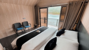 Una habitación de hotel con una cama, dos sillas, una mesita y vistas al exterior.