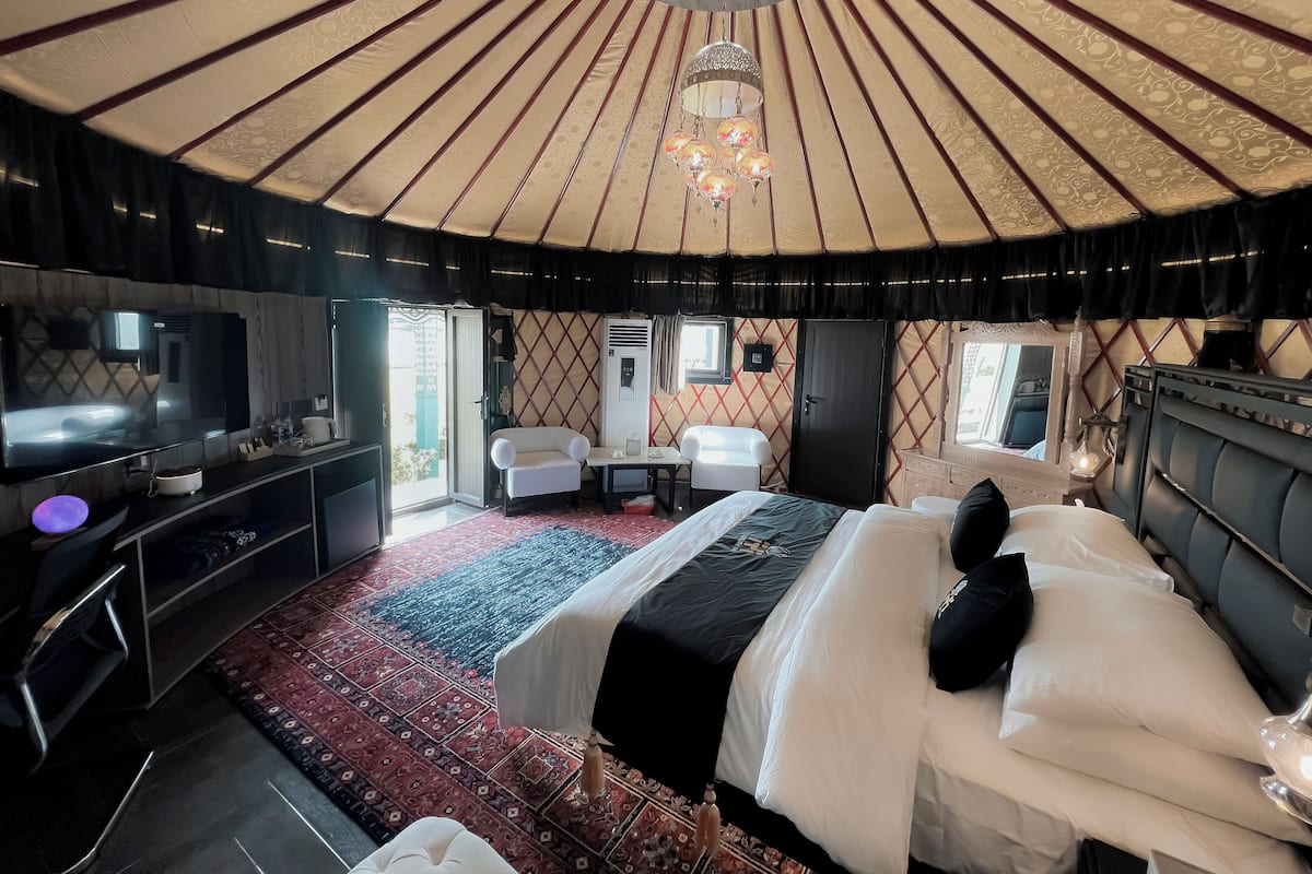 Une pièce de style yourte comprenant un lit, une télévision, un bureau et une chaise.