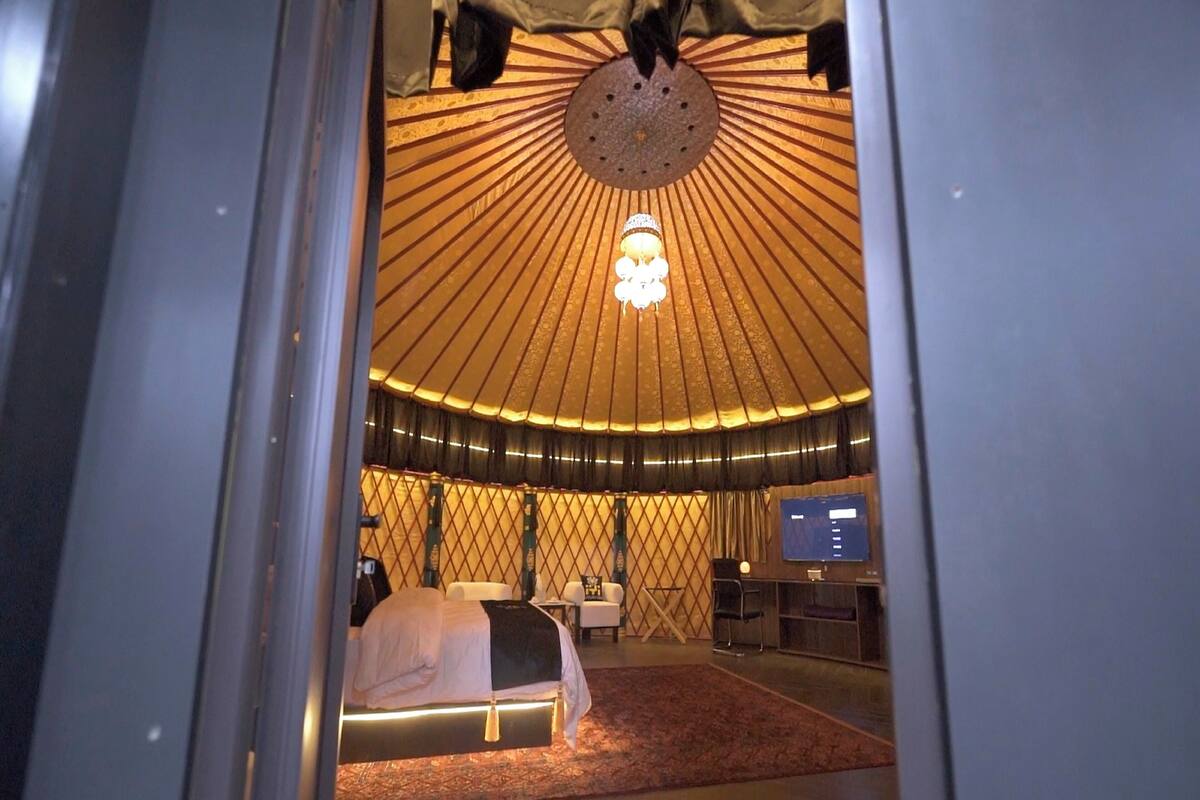 Une pièce aménagée comme une yourte, avec un lit, un bureau et un téléviseur.
