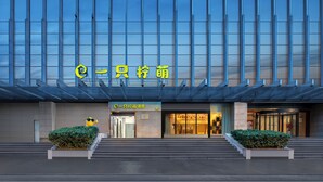 Un bâtiment moderne doté d’une façade en verre et d’une enseigne indiquant l’entrée de l’hôtel.